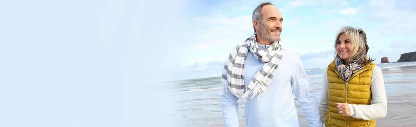 Older couple walking on the beach | Dental Implants Poway CA